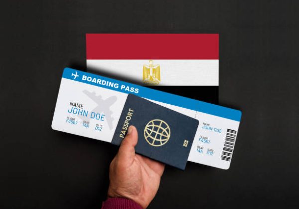 Hand holds passport and boarding pass with flag of Egypt